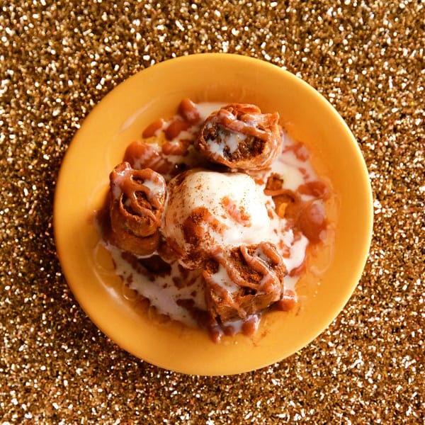 Cuban dessert with fried dough, vanilla ice cream, and cinnamon on a yellow plate.