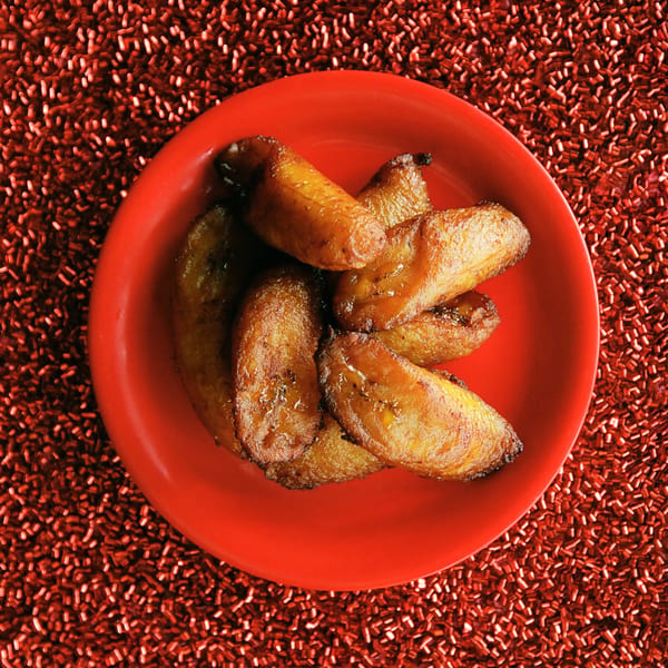 Sweet fried plantains, known as maduros, on a vibrant red plate at Rancho Alegre Cuban Restaurant.